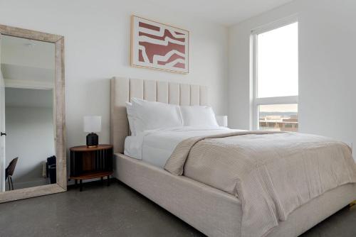 une chambre blanche avec un grand lit et un miroir dans l'établissement Blueground New Tacoma balcony nr Union Station SEA-955, à Tacoma