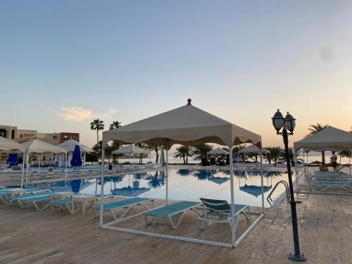 a swimming pool with lounge chairs and umbrellas at منتجع تالابيه العقبة in Aqaba