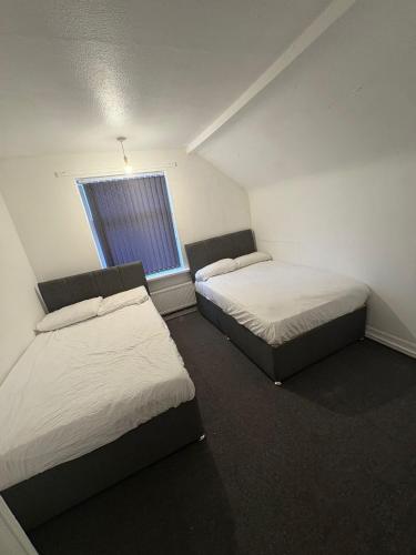 two beds in a small room with a window at WOLVES Stay in Wolverhampton