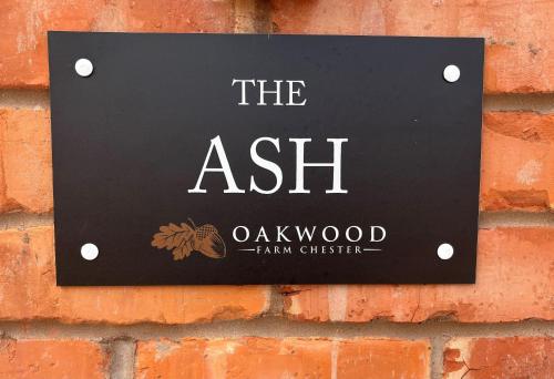 a sign on a brick wall with the ash oakwood firm ghetto at Oakwood Farm Barns in Chester