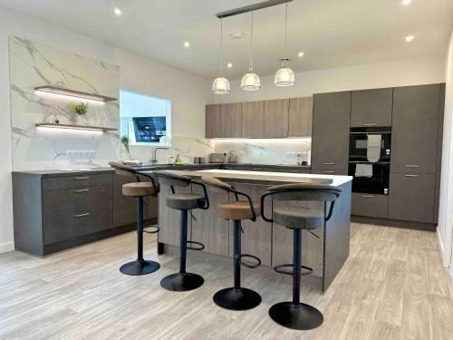 - une cuisine avec un îlot doté de tabourets de bar dans l'établissement Isles View, Luxury Modern Spacious Villa in Kirkwall, à Orkney