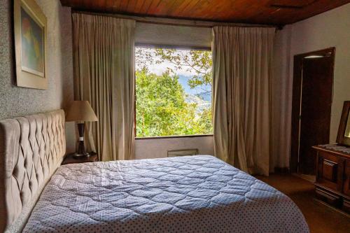 um quarto com uma cama e uma janela grande em Refúgio na Serra de Petrópolis simples e acolhedor em Petrópolis