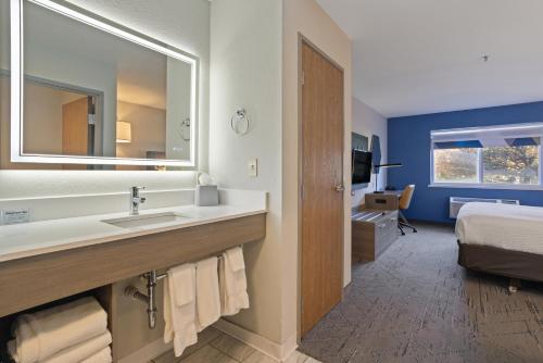a bathroom with a sink and a mirror and a bed at Holiday Inn Express Hotel & Suites Torrington by IHG in Torrington