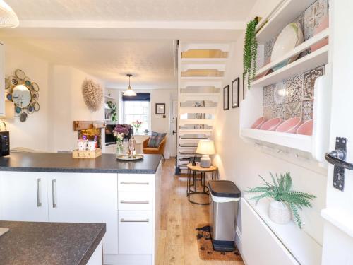 a kitchen and living room with white cabinets and a staircase at Periwinkle Cottage in Conwy