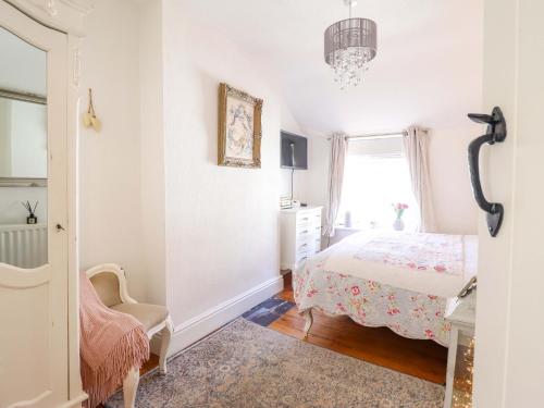 a bedroom with a bed and a chair and a window at Periwinkle Cottage in Conwy