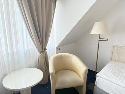 1 dormitorio con silla, mesa y cama en HOTEL S Norderstedt, en Norderstedt
