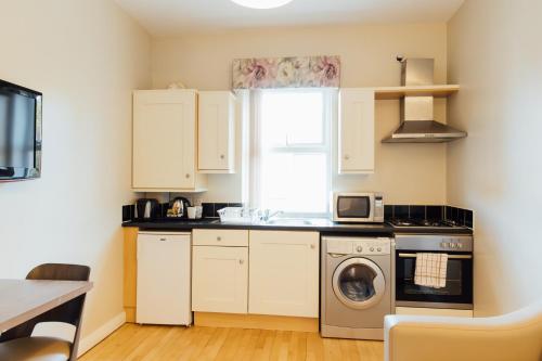 a kitchen with white cabinets and a washer and dryer at The Malone Hotel in Belfast