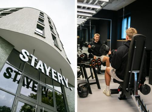 ボーフムにあるSTAYERY Bochum Ehrenfeldの建物の前にあるジムでダンベルを持つ男性