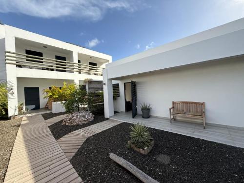 a white house with a bench in front of it at Boho Garden Jan Thiel Apt C in Jan Thiel
