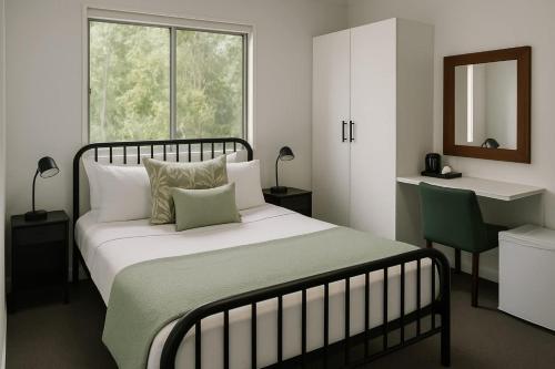 a bedroom with a bed and a desk and a window at Tranquil Queen Room & Pool in Upper Mudgeeraba