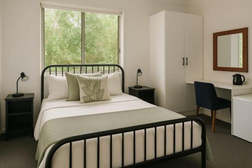 a bedroom with a bed and a desk and a window at Tranquil Queen Room & Pool in Upper Mudgeeraba