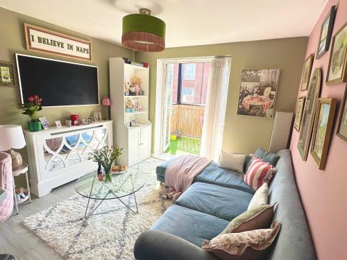 Una sala de estar con un sofá azul y un televisor. en Pink Paradise, en Dunstable