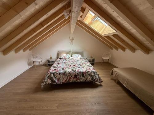 ein Schlafzimmer mit einem Bett und zwei Stühlen im Dachgeschoss in der Unterkunft Charmante maison rénovée avec terrasse et jardin in Crillat