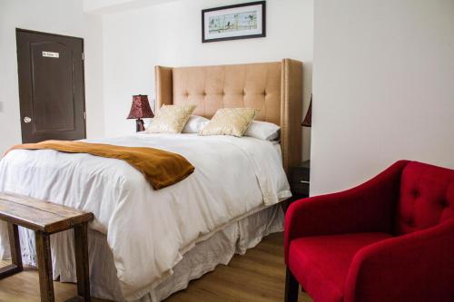 a bedroom with a large bed and a red chair at Meraki Boutique Hotel in Guatemala