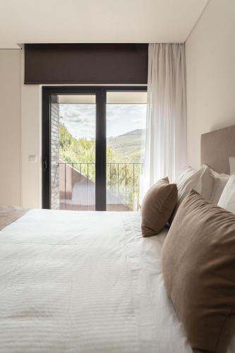 a bedroom with a white bed with a large window at Casa do Ferrão in Covas do Douro