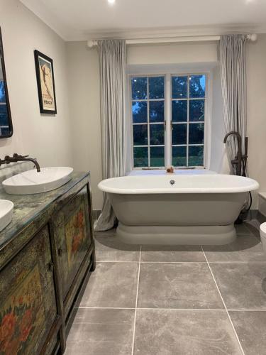 a large bathroom with a large tub and a window at Stunning Countryside House with Pool and Hot Tub in Hankerton