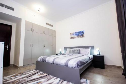 a bedroom with a large bed with white walls at Fully Furnished Brand new 1BHK at Warsan in Dubai