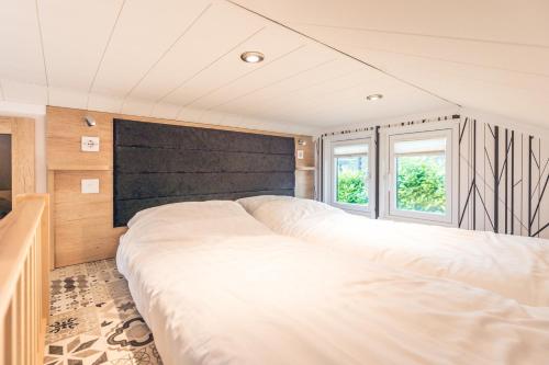 a large white bed in a room with two windows at Vakantiepark Ackersate in Voorthuizen