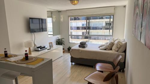 Apartamento en POCITOS vista al mar في مونتيفيديو: غرفة نوم بها سرير ومكتب وتلفزيون