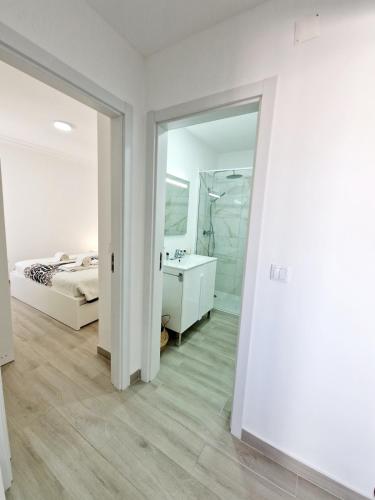 a white bedroom with a bed and a mirror at Blue Sun Armação in Armação de Pêra