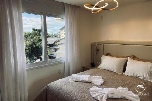 a bedroom with towels on a bed with a window at Apartamento Novo Aconchegante e Moderno em Canela in Canela