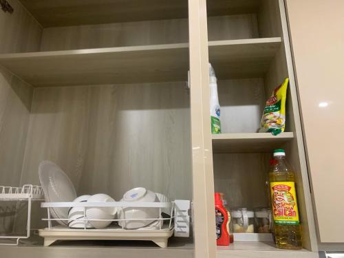 a cupboard with dishes and other items in a kitchen at Vinhomes Smart City by Chill D Homestay in Phú Thú