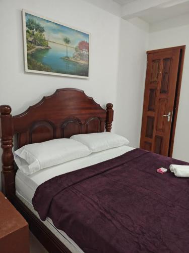 a bedroom with a wooden bed with a picture on the wall at suíte feliz in Belém