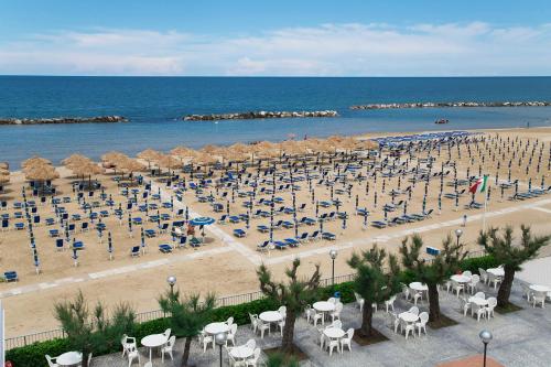 a beach with chairs and umbrellas and the ocean at Hotel Mara in Ortona