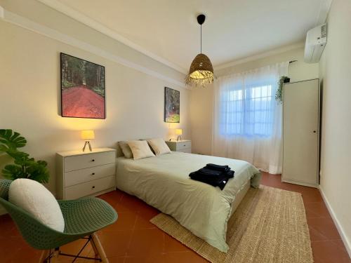 a bedroom with a bed and a chair in it at Biscoitos-Upstudio in Biscoitos