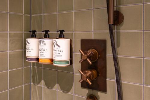 Mollie's Manchester في مانشستر: حمام فيه ثلاث زجاجات شامبو على الحائط