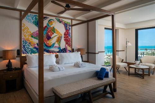 a bedroom with a large bed with a painting on the wall at Ocean Allure Costa Mujeres - Adults Only - All Inclusive in Costa Mujeres