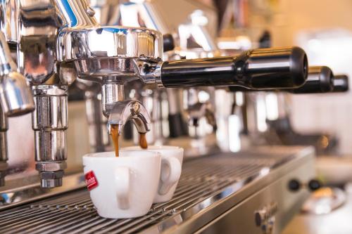 a coffee maker is pouring coffee into two cups at Hotel Mara in Ortona