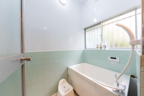 Un baño con bañera, inodoro y ventana. en 駅徒歩6分 4ldk 82平米 最大8人 成田空港から約40分 和と洋の美しい室内 隠れ家 せつきの宿, en Matsudo
