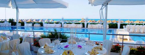 a restaurant with white tables and chairs and the ocean at Hotel Mara in Ortona
