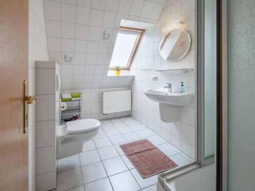 a white bathroom with a sink and a toilet at Norderhof Hansen - Ferienhaus in Nordstrand