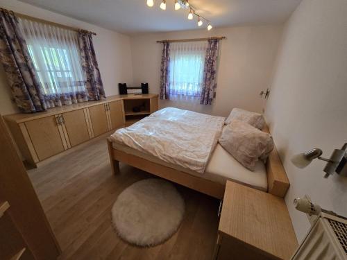 a bedroom with a bed and a desk and windows at Ferienwohnung WIEKI in Puchreit