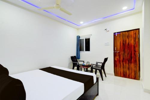 a bedroom with a bed and a table and chairs at HOTEL O SVR Jb Cricket ground in Pedda Ambarpet