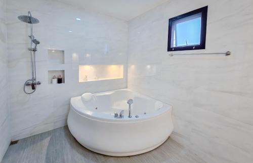 une salle de bain blanche avec une baignoire et une fenêtre dans l'établissement Luekpanee pool villa pranburi, à Ban Nong Ban Kao