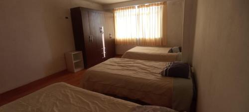 a hotel room with two beds and a window at Apartment, with kitchen, garage and laundry in Tacna