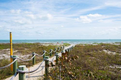 een hek op een strand met de oceaan op de achtergrond bij Beach Townhome Steps from Downtown Cocoa Beach in Cocoa Beach