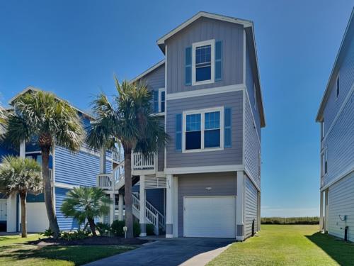 a house with palm trees in front of it at So Serene in Galveston