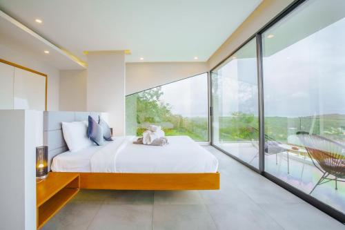 a bedroom with a large bed and large glass windows at Yamu Hills Panoramic Ocean View 6 Bed Luxury Vila in Phuket Town
