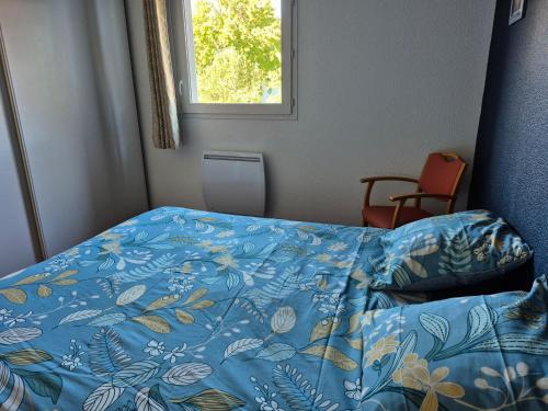 a bedroom with a bed with a blue comforter and a window at Couleur océan in Saint-Paul-lès-Dax