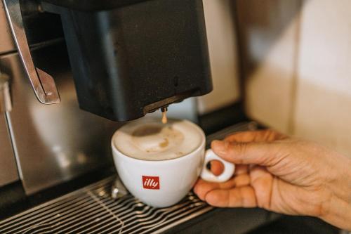 a person holding a cup of coffee in a coffee machine at Villa Di Sotto in Castelnuovo Berardenga