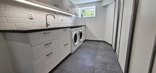 a white kitchen with a sink and washing machines at Apartment in Skärhamn within walking distance to the beach in Toftenäs