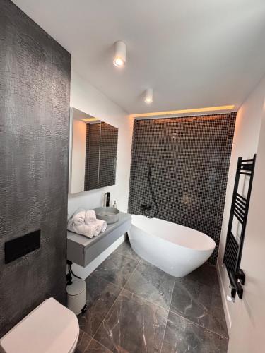 a bathroom with a tub and a toilet and a sink at Sky View Penthouse in Craiova