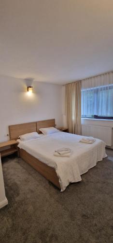 a bedroom with a large white bed with a window at Cheile Braitei in Lupeni