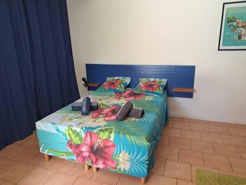 a bedroom with a bed with a blue bedspread with flowers at Studio Kerbignon, Piscine privée in Case-Pilote
