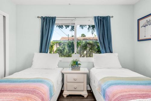 two beds in a room with a window at Relaxing Salt Pool & Spa, Walk to Key Lime House! in Lantana