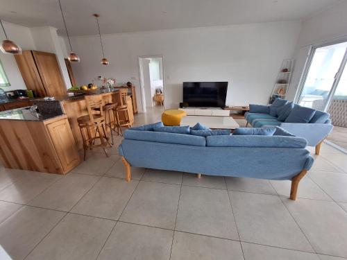 ein Wohnzimmer mit einer blauen Couch und eine Küche in der Unterkunft House on a rock in Anse aux Pins